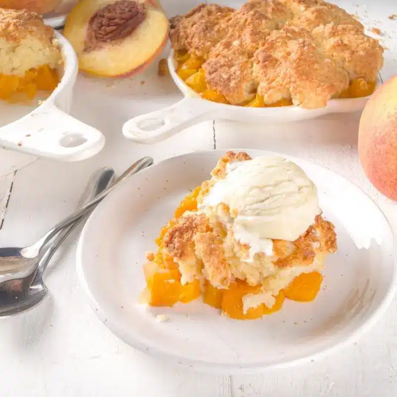 Peach cobbler plated up with a scoop of vanilla ice cream top.