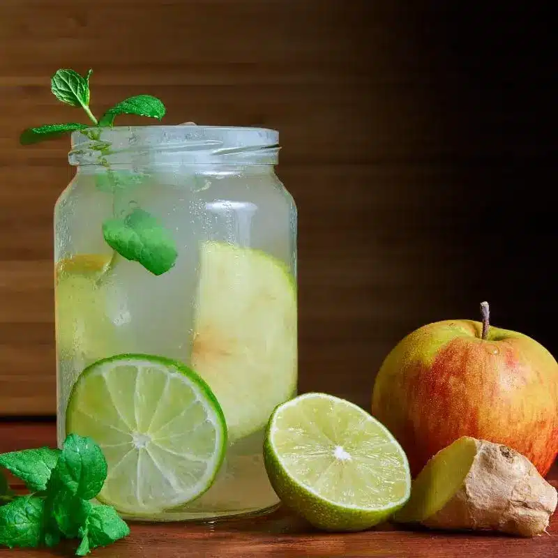 Apple, lemon, mint switchel in a mason jar with the ingredients next to it.